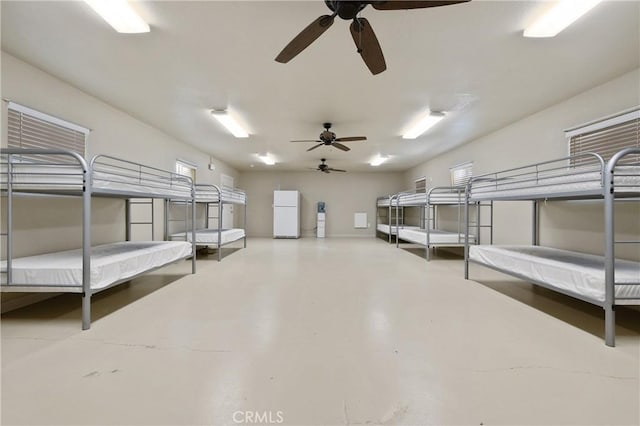 basement with ceiling fan and white refrigerator