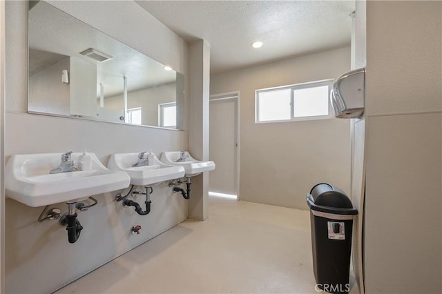 bathroom featuring a textured ceiling, concrete floors, and sink