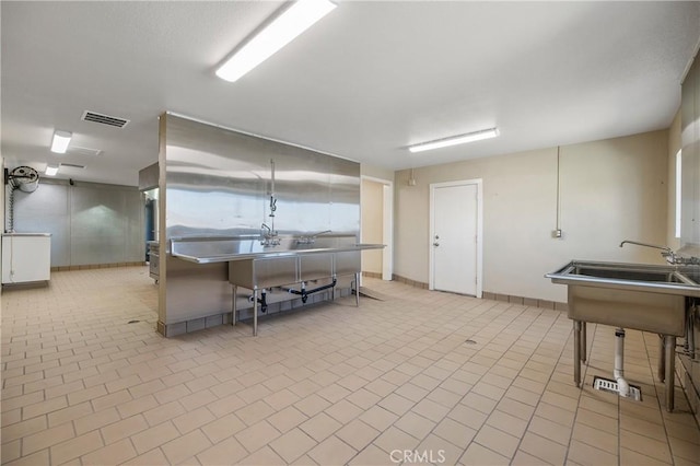 interior space featuring a breakfast bar area, light tile patterned floors, stainless steel counters, and white cabinetry