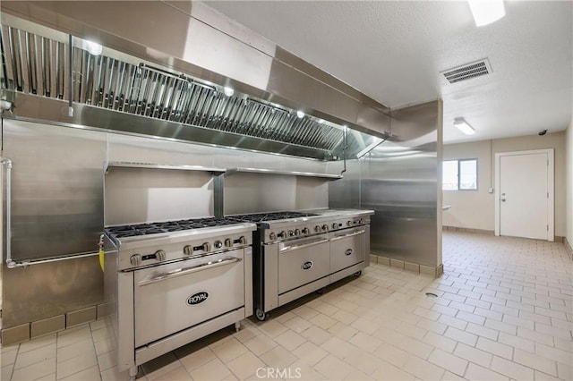 kitchen featuring a textured ceiling, light tile patterned floors, and high end stove