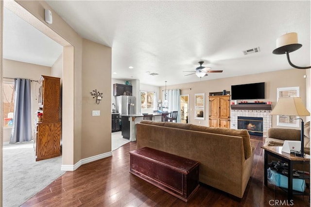 living room with ceiling fan, dark hardwood / wood-style flooring, and a tiled fireplace