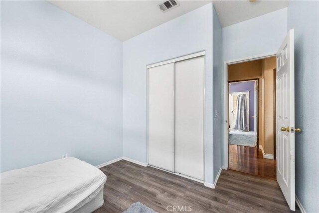 bedroom with dark wood-type flooring and a closet