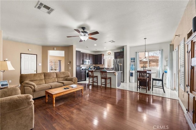 living room with ceiling fan, a textured ceiling, and hardwood / wood-style flooring