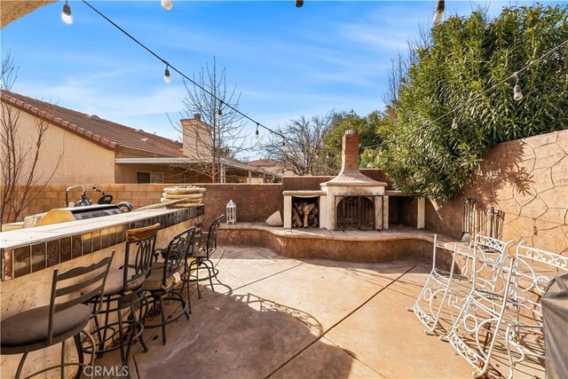 view of patio with an outdoor fireplace and an outdoor bar