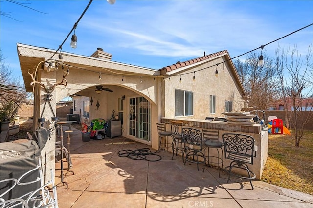 back of house featuring ceiling fan, exterior bar, and a patio