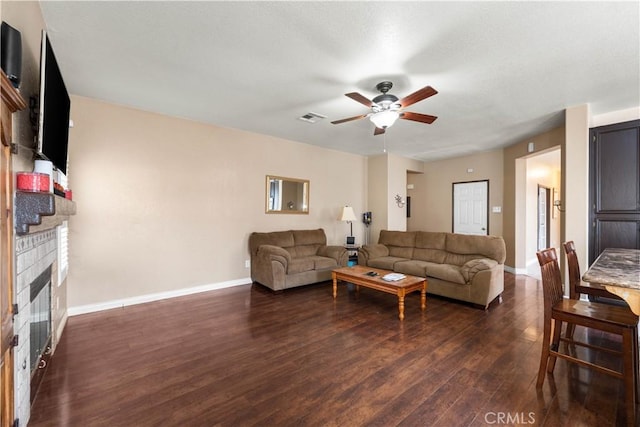 living room featuring ceiling fan, a fireplace, and dark hardwood / wood-style floors