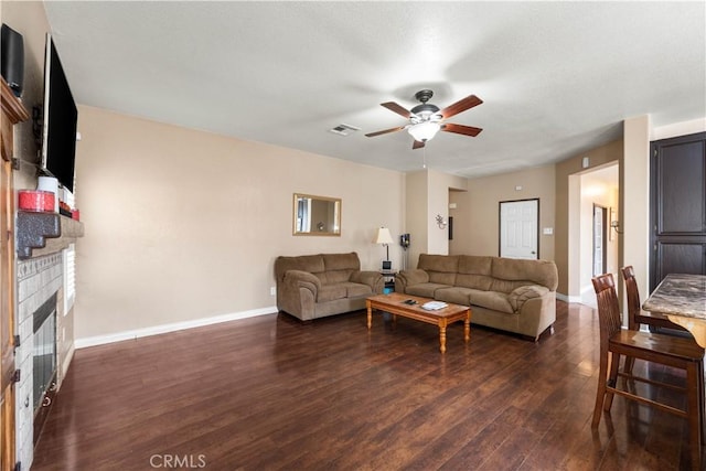 living room featuring ceiling fan, dark hardwood / wood-style flooring, and a fireplace