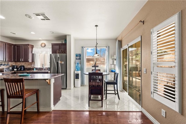 kitchen featuring light tile patterned flooring, stainless steel fridge, hanging light fixtures, and sink