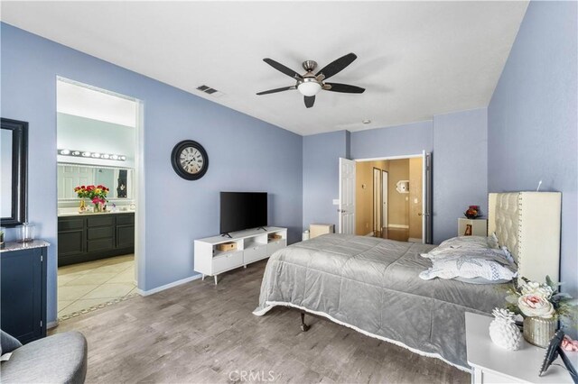 bedroom featuring ceiling fan, light hardwood / wood-style floors, and connected bathroom