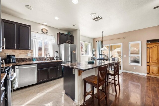 kitchen with a kitchen island, pendant lighting, sink, a breakfast bar area, and stainless steel appliances