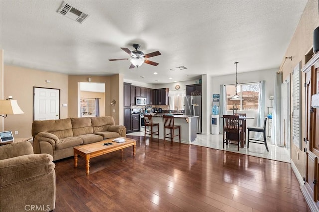 living room featuring ceiling fan, a textured ceiling, and hardwood / wood-style flooring