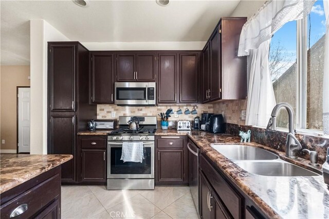 kitchen featuring decorative backsplash, sink, dark brown cabinetry, stainless steel appliances, and dark stone counters