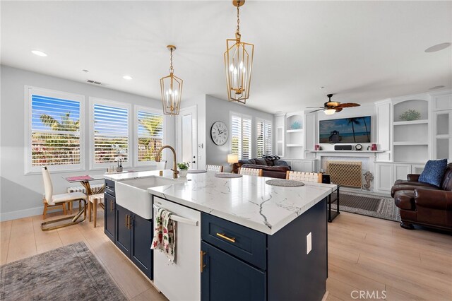 kitchen with built in shelves, ceiling fan, sink, a kitchen island with sink, and white dishwasher