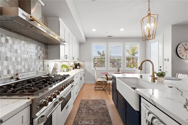 kitchen with pendant lighting, decorative backsplash, white cabinetry, range with two ovens, and ventilation hood