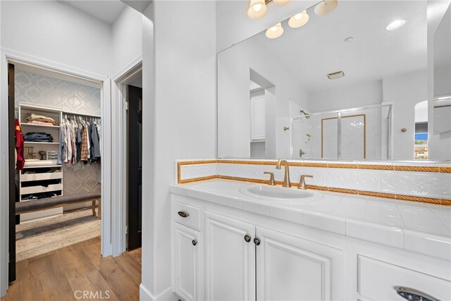 bathroom featuring hardwood / wood-style flooring, walk in shower, and vanity