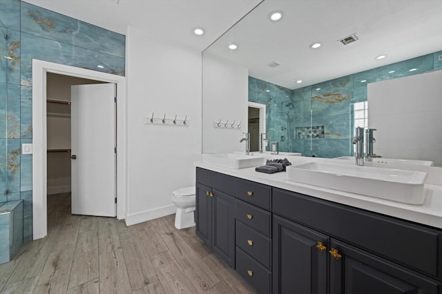 bathroom with toilet, a shower with shower door, hardwood / wood-style floors, and vanity