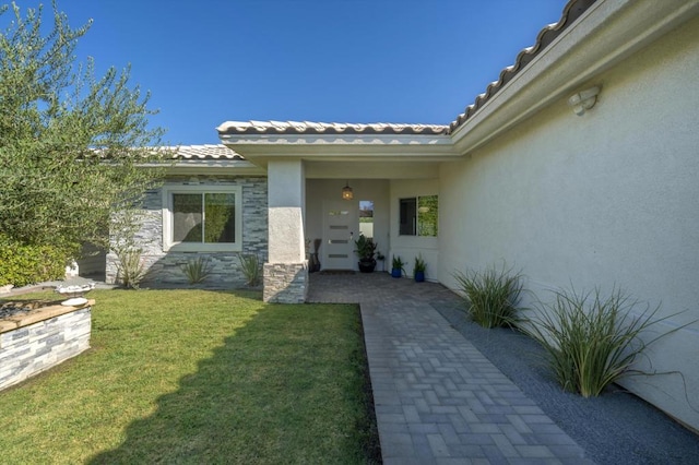 view of exterior entry featuring a yard