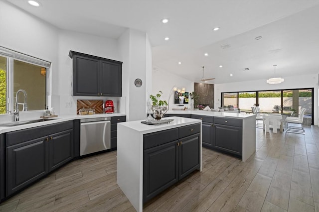 kitchen featuring kitchen peninsula, ceiling fan, a center island, dishwasher, and sink