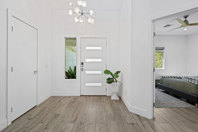 entrance foyer featuring ceiling fan with notable chandelier and light hardwood / wood-style flooring