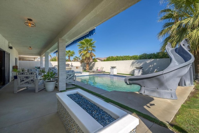 view of swimming pool with an outdoor fire pit, a patio area, and a water slide