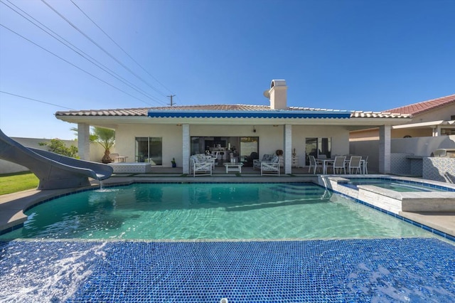 back of property with a swimming pool with hot tub and a patio