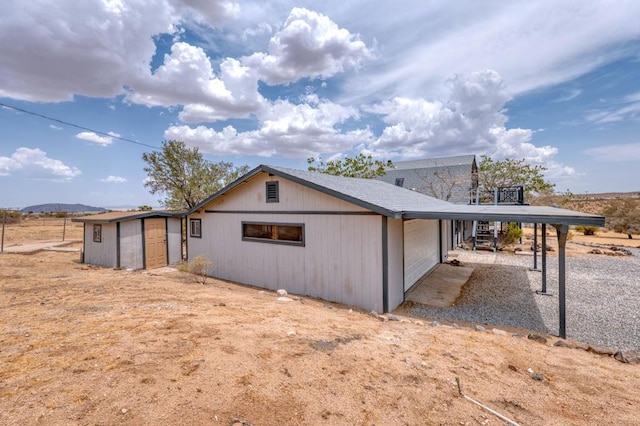 back of property with a carport, a mountain view, and an outdoor structure