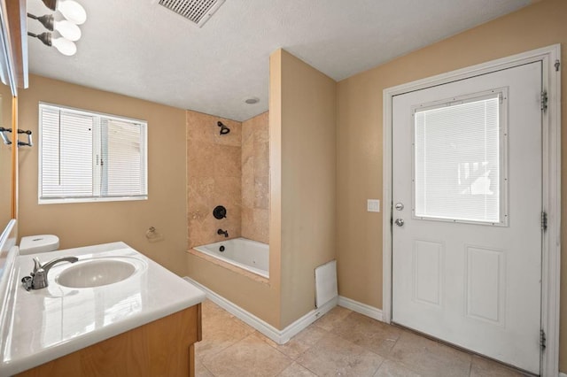 bathroom with tile patterned floors, vanity, and tiled shower / bath