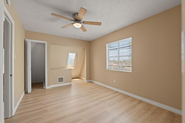 unfurnished bedroom featuring ceiling fan, a textured ceiling, a skylight, and light wood-type flooring