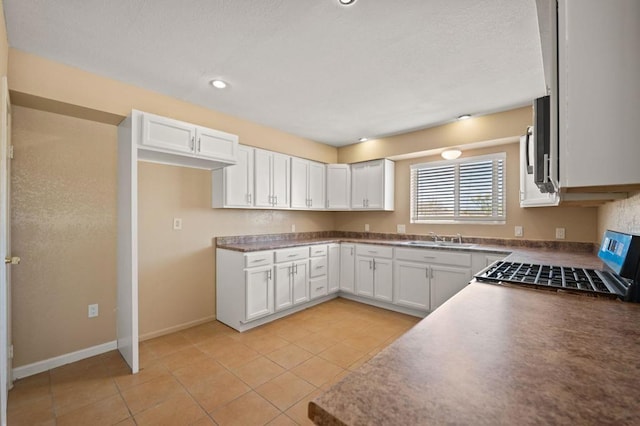 kitchen with sink, white cabinets, range, and light tile patterned flooring