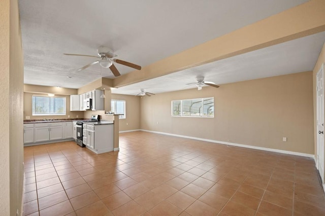 kitchen with light tile patterned flooring, white cabinetry, plenty of natural light, and stainless steel range with gas cooktop