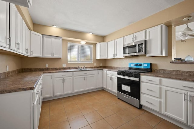 kitchen with white cabinets, appliances with stainless steel finishes, sink, ceiling fan, and light tile patterned floors