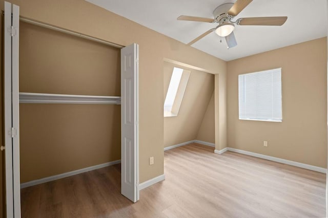 unfurnished bedroom with ceiling fan, light wood-type flooring, a skylight, and a closet