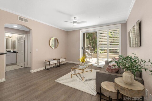 living room with ceiling fan, crown molding, and wood-type flooring