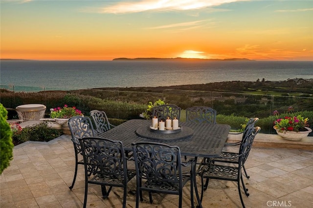 patio terrace at dusk featuring a water view