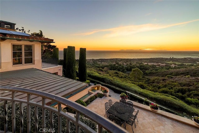 balcony at dusk with a water view and a patio