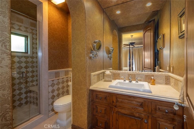 bathroom featuring toilet, ceiling fan, walk in shower, and vanity