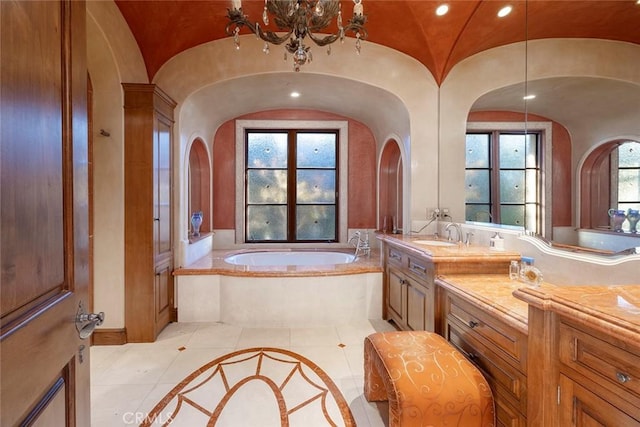 bathroom with vanity, tile patterned flooring, vaulted ceiling, an inviting chandelier, and a relaxing tiled tub