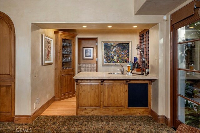 bar with sink and light hardwood / wood-style flooring