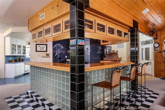 bar featuring wooden ceiling, white cabinetry, decorative backsplash, and dark colored carpet