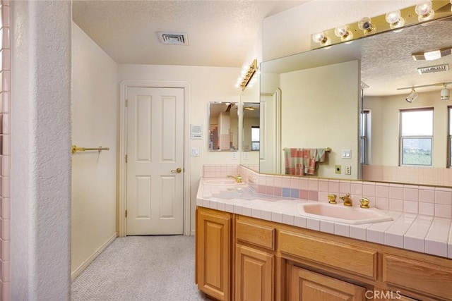 bathroom with a textured ceiling, backsplash, and vanity