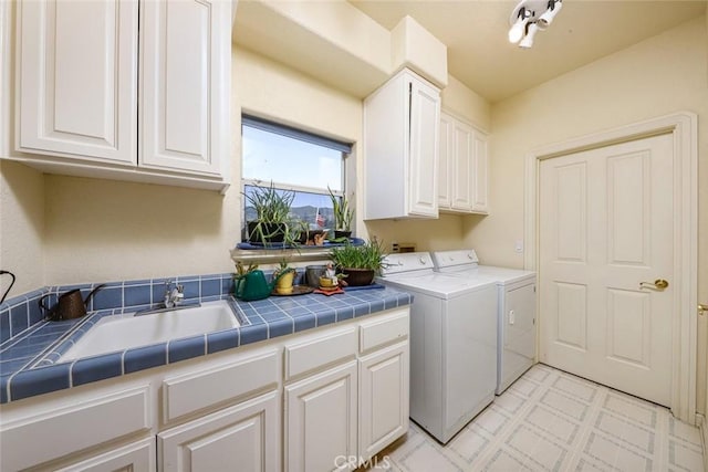 washroom featuring cabinets, sink, and washing machine and dryer