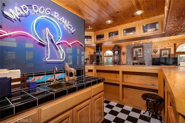 bar with tile counters, sink, wood walls, and wooden ceiling