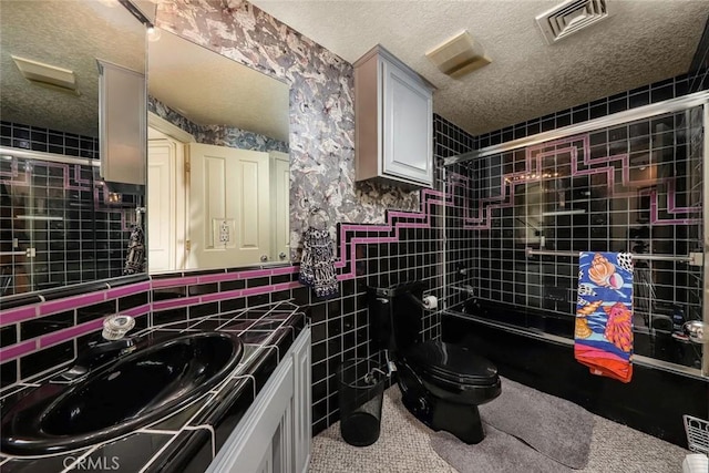 full bathroom featuring toilet, vanity, tile patterned flooring, tiled shower / bath combo, and a textured ceiling