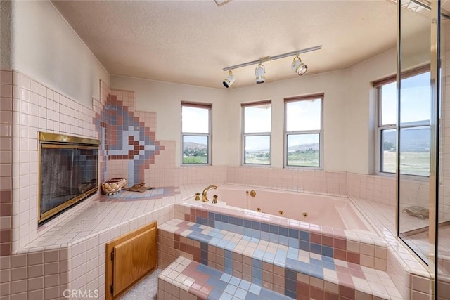 bathroom with tiled bath and a textured ceiling