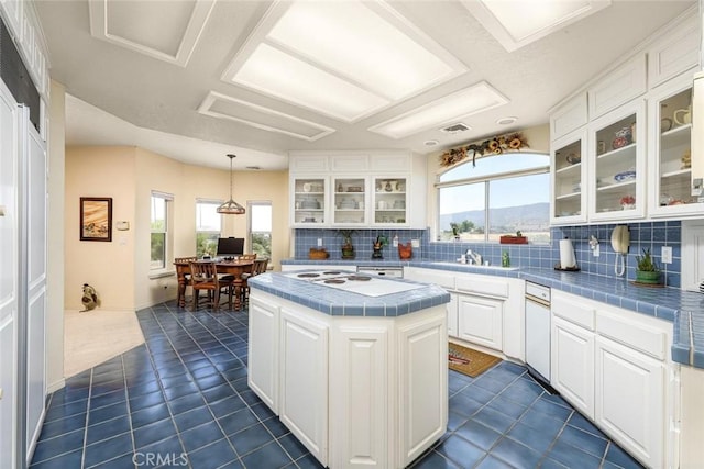 kitchen featuring pendant lighting, white cabinetry, tile counters, and a kitchen island