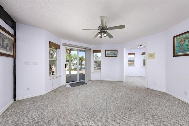 spare room featuring light carpet, ceiling fan, and a textured ceiling