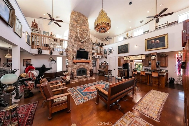 living room featuring ceiling fan, a towering ceiling, and a stone fireplace