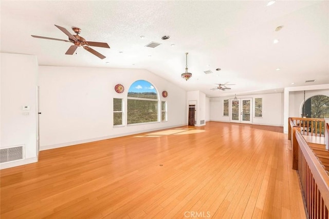 unfurnished living room featuring lofted ceiling, light wood-type flooring, visible vents, and a ceiling fan