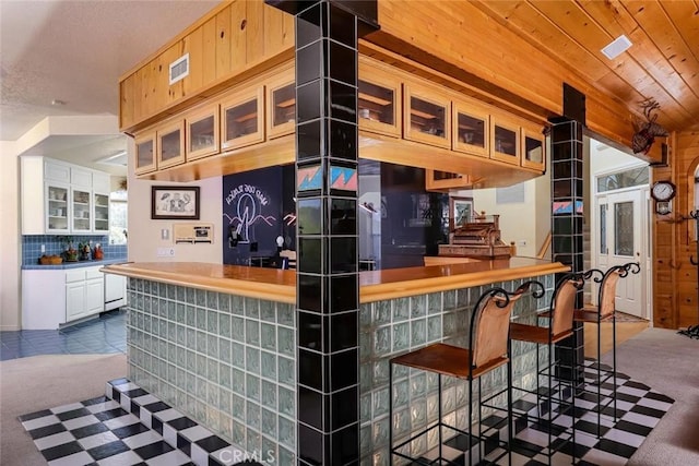 kitchen with tile patterned flooring, carpet floors, wood ceiling, visible vents, and tasteful backsplash