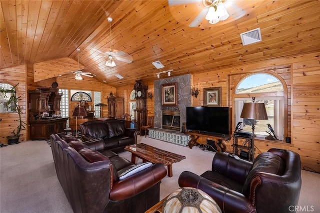 living room with vaulted ceiling, wood walls, carpet, and visible vents